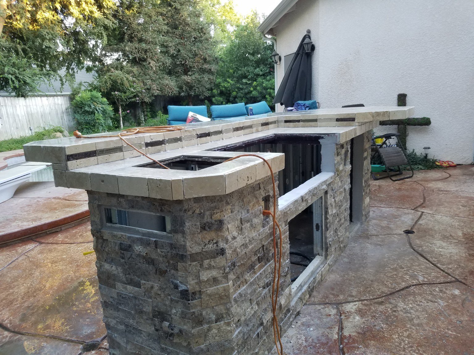 Outdoor kitchen during construction, showing stone masonry and countertop work