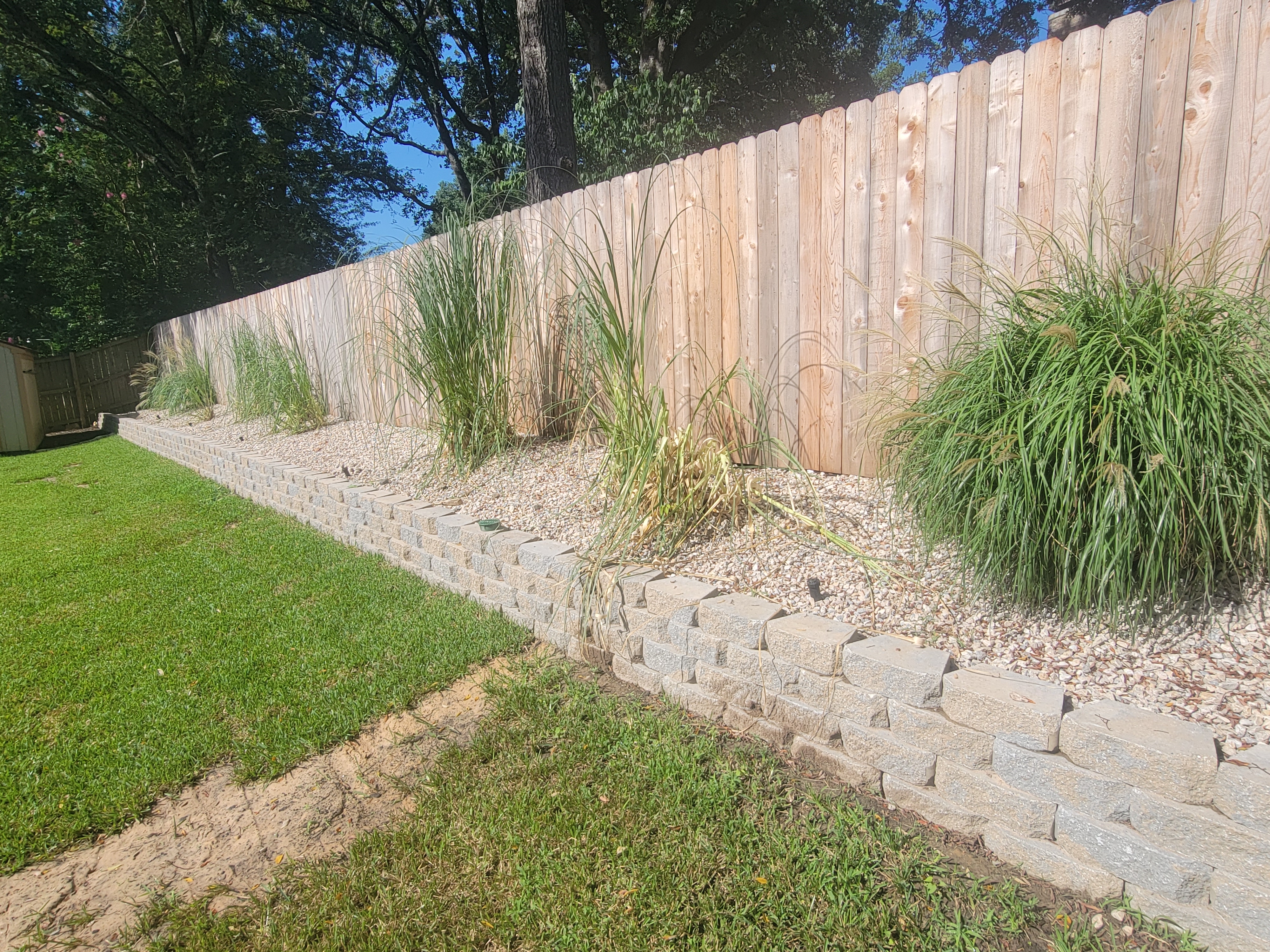 Long finished block retaining wall integrated with a landscaped yard