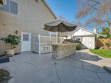 Completed outdoor kitchen and stone bar in its finished patio and backyard setting